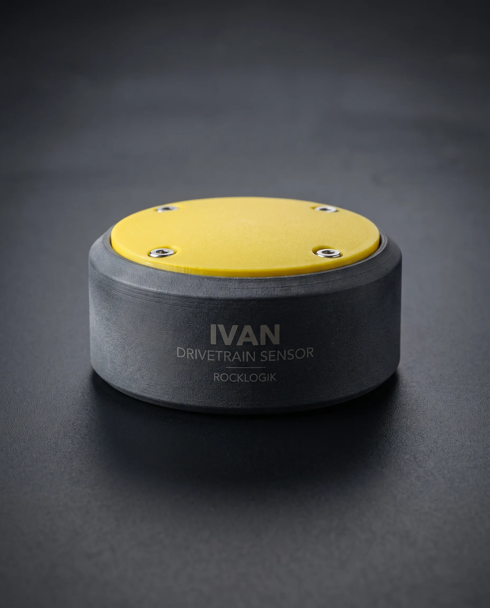 Studio rendering of the RockLogik Scout Sensor: a squat dark-grey printed-nylon puck with a yellow lid held by four screws, sitting flat on its base, etched with its product name, drivetrain sensor, RockLogik.
